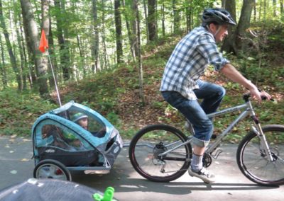 Man riding bike pulling children in kiddie trailer